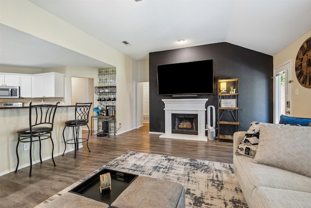 living room with dark hardwood / wood-style flooring and vaulted ceiling