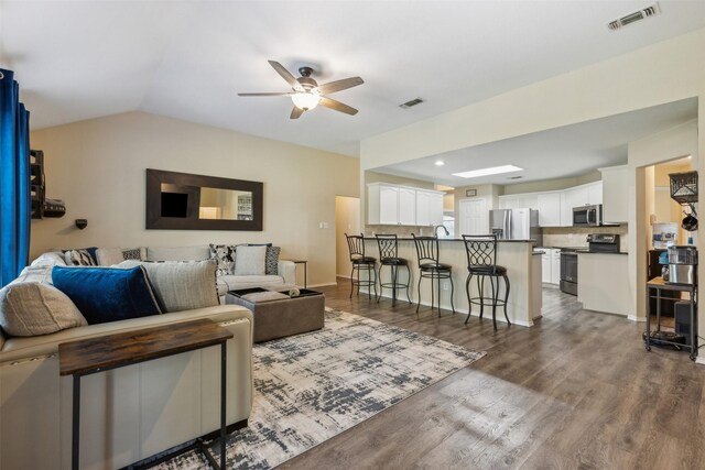 living room featuring ceiling fan, dark wood-type flooring, and lofted ceiling