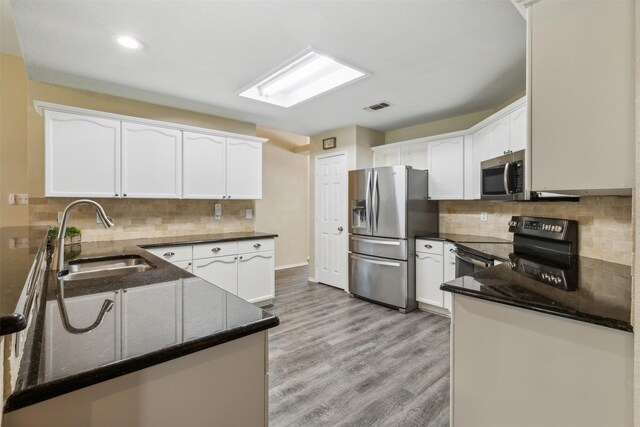 kitchen with kitchen peninsula, stainless steel appliances, white cabinetry, and sink