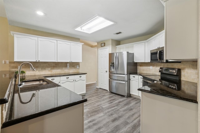 kitchen with sink, stainless steel appliances, kitchen peninsula, and white cabinets