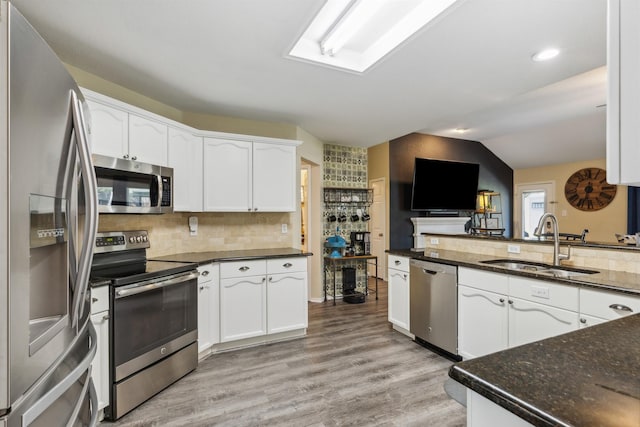 kitchen with white cabinetry, sink, vaulted ceiling, and stainless steel appliances