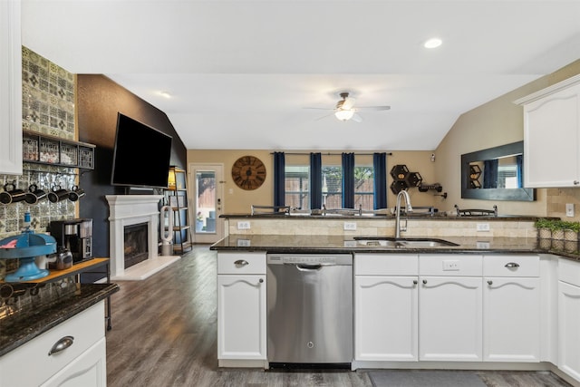 kitchen with kitchen peninsula, white cabinets, sink, dishwasher, and lofted ceiling