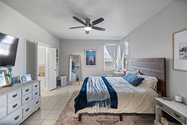 tiled bedroom featuring ensuite bath, ceiling fan, and a textured ceiling