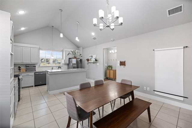 tiled dining area featuring high vaulted ceiling and an inviting chandelier