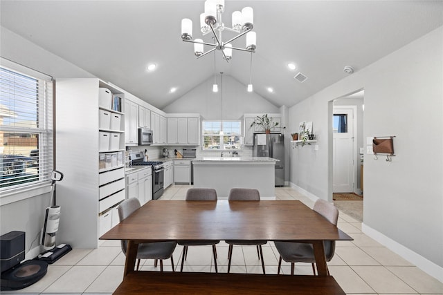 tiled dining space with lofted ceiling and an inviting chandelier