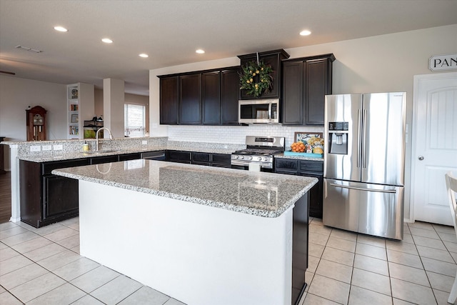 kitchen with a center island, sink, stainless steel appliances, light stone counters, and kitchen peninsula