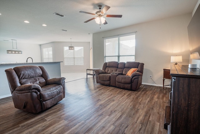 living room featuring ceiling fan, sink, and dark hardwood / wood-style floors