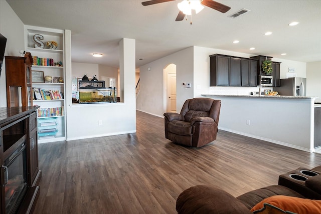 living room featuring dark hardwood / wood-style floors, ceiling fan, and built in features