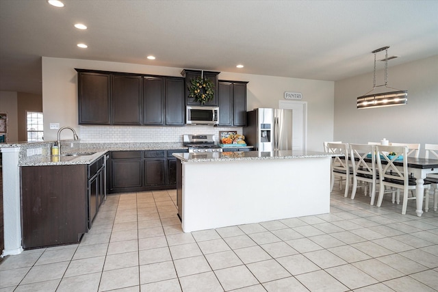 kitchen featuring decorative backsplash, appliances with stainless steel finishes, dark brown cabinets, sink, and hanging light fixtures