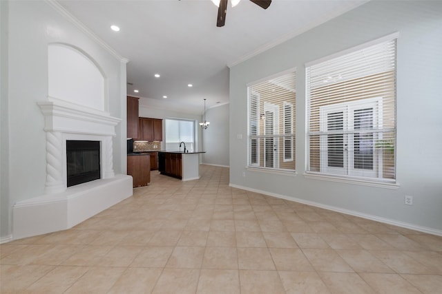 unfurnished living room featuring light tile patterned floors, ceiling fan with notable chandelier, crown molding, and sink