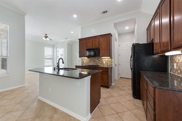 kitchen featuring ceiling fan, sink, an island with sink, decorative backsplash, and black appliances