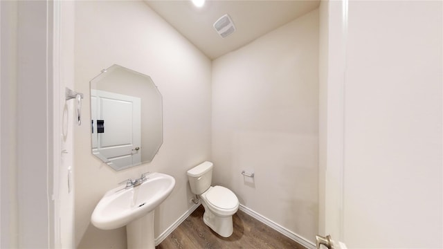 bathroom featuring sink, wood-type flooring, vaulted ceiling, and toilet