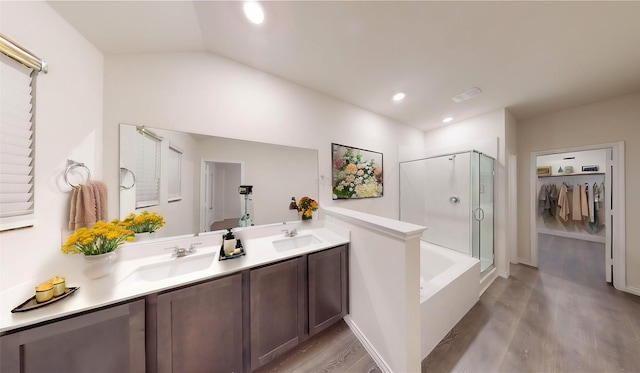 bathroom with vanity, wood-type flooring, shower with separate bathtub, and vaulted ceiling