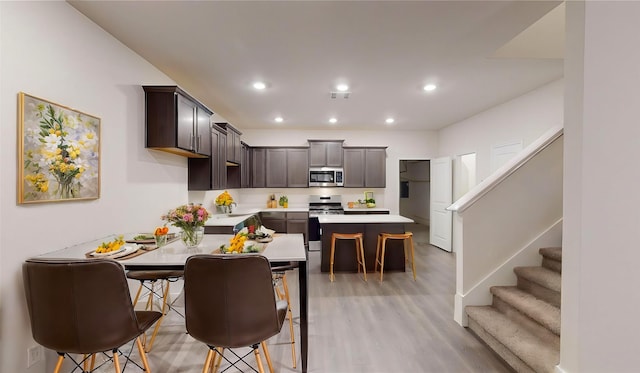 kitchen with a breakfast bar area, light hardwood / wood-style flooring, a kitchen island, and stainless steel appliances