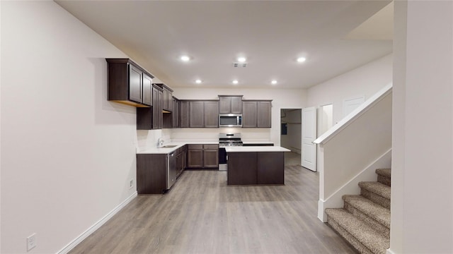 kitchen featuring sink, light hardwood / wood-style flooring, a kitchen island, dark brown cabinetry, and stainless steel appliances