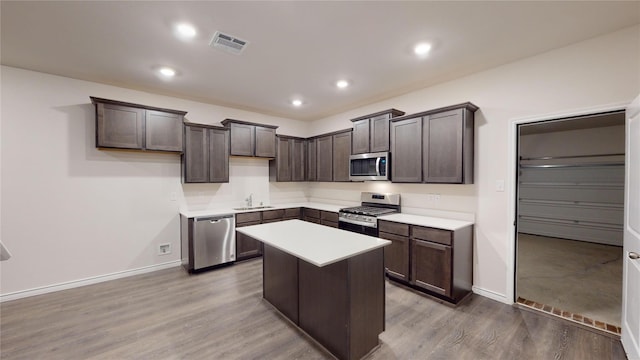 kitchen with hardwood / wood-style floors, sink, dark brown cabinets, a kitchen island, and stainless steel appliances