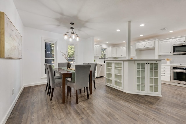 dining area with wood-type flooring, an inviting chandelier, and sink