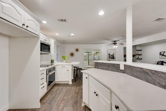 kitchen featuring appliances with stainless steel finishes, dark hardwood / wood-style flooring, white cabinetry, and ceiling fan