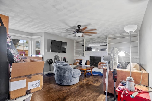 living room with a textured ceiling, dark hardwood / wood-style floors, ceiling fan, and a fireplace