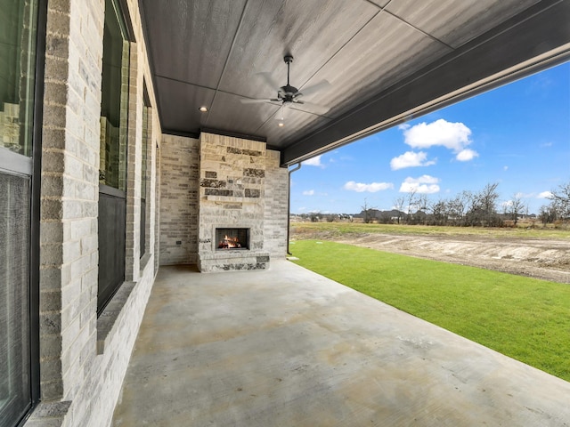 view of patio with an outdoor stone fireplace and ceiling fan