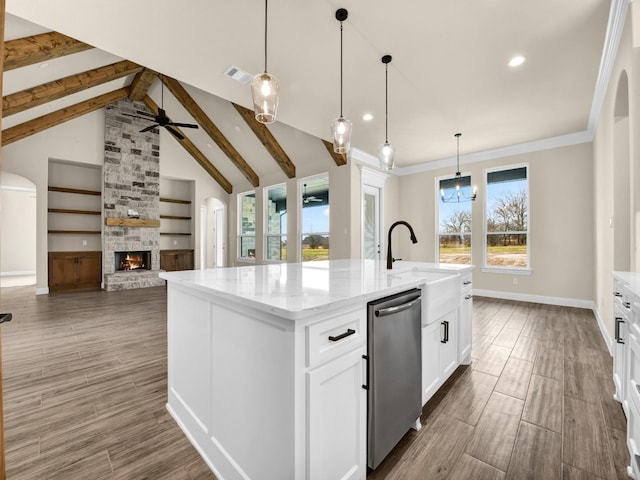 kitchen with a kitchen island with sink, pendant lighting, dishwasher, a fireplace, and white cabinetry