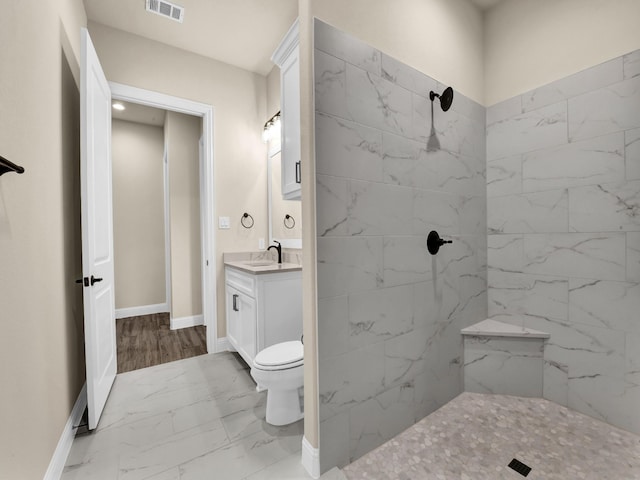 bathroom featuring tiled shower, vanity, and toilet