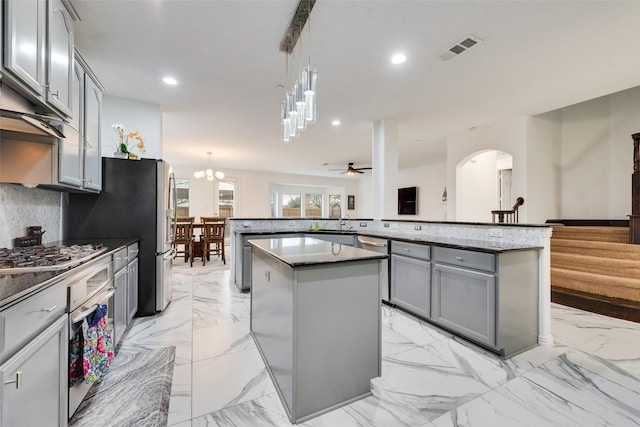 kitchen featuring stainless steel appliances, tasteful backsplash, a kitchen island, and hanging light fixtures