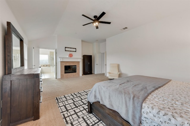 bedroom with ceiling fan, a fireplace, light carpet, and vaulted ceiling