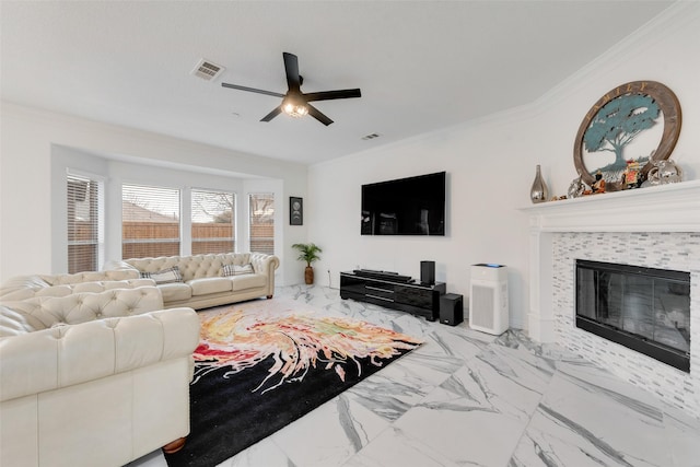 living room with ceiling fan, ornamental molding, and a tile fireplace