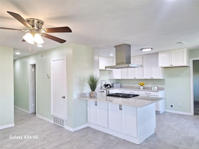 kitchen with white cabinets, kitchen peninsula, island exhaust hood, and stainless steel gas cooktop