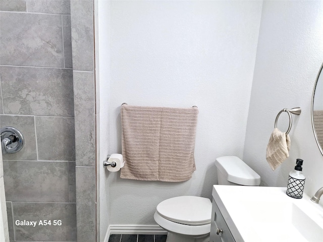 bathroom featuring tiled shower, vanity, and toilet