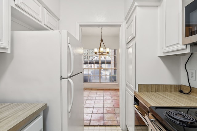 kitchen featuring light tile patterned flooring, decorative light fixtures, white fridge, white cabinetry, and a chandelier