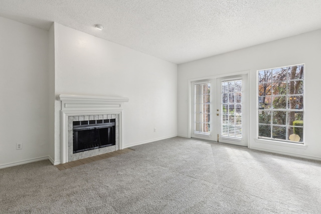 unfurnished living room featuring carpet, a textured ceiling, and a tiled fireplace