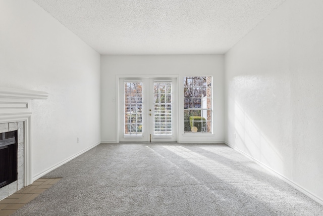 unfurnished living room featuring a fireplace, light colored carpet, and a textured ceiling