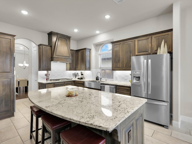 kitchen featuring dark brown cabinetry, sink, custom exhaust hood, a center island, and appliances with stainless steel finishes