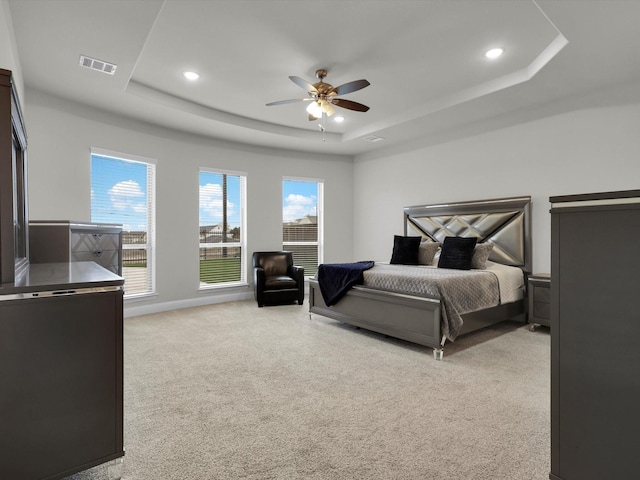 carpeted bedroom with a raised ceiling and ceiling fan