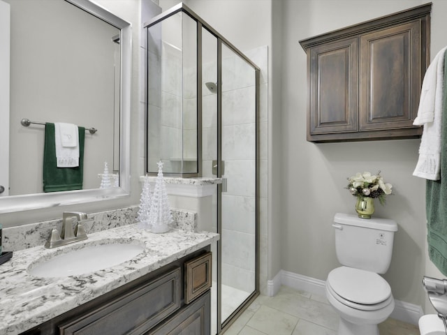 bathroom featuring a stall shower, toilet, vanity, and baseboards