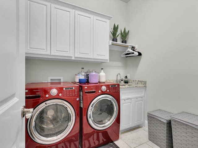 clothes washing area with cabinet space, light tile patterned floors, washing machine and dryer, and a sink