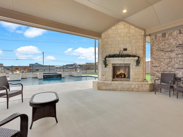 view of patio featuring a pool with connected hot tub, an outdoor stone fireplace, and fence