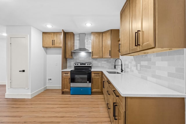 kitchen featuring wall chimney exhaust hood, sink, stainless steel range with electric cooktop, light hardwood / wood-style floors, and backsplash