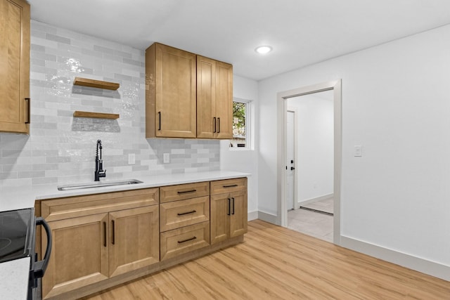 kitchen featuring tasteful backsplash, sink, light wood-type flooring, and black / electric stove