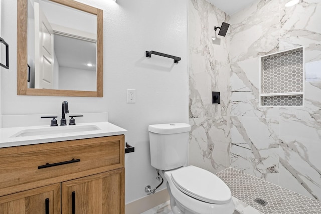 bathroom with vanity, a tile shower, and toilet