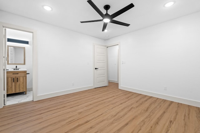 unfurnished bedroom featuring sink, light hardwood / wood-style flooring, ceiling fan, and ensuite bathroom