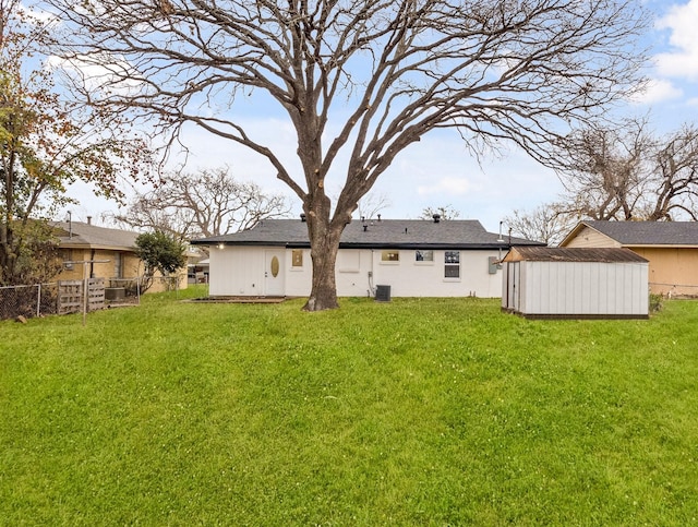 rear view of house featuring central AC unit, a shed, and a lawn