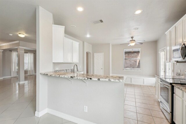 kitchen featuring kitchen peninsula, stainless steel appliances, white cabinets, and light stone countertops