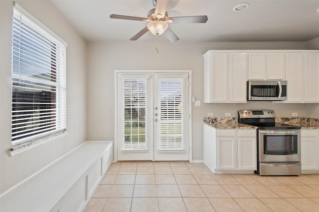 kitchen featuring light tile patterned floors, stainless steel appliances, white cabinetry, and light stone counters