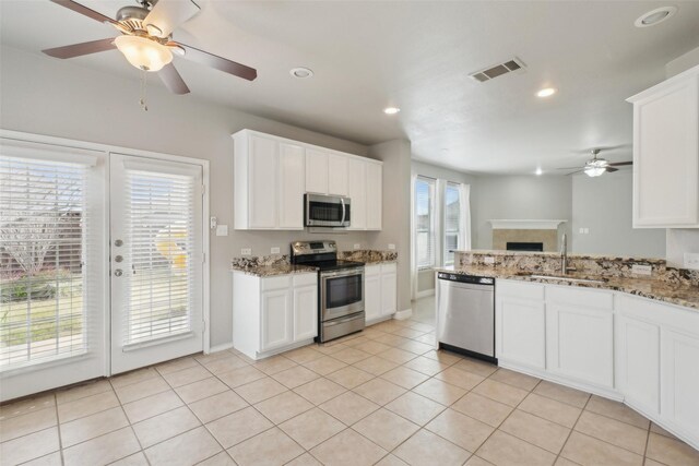 kitchen with white cabinetry, sink, stainless steel appliances, light stone counters, and light tile patterned flooring