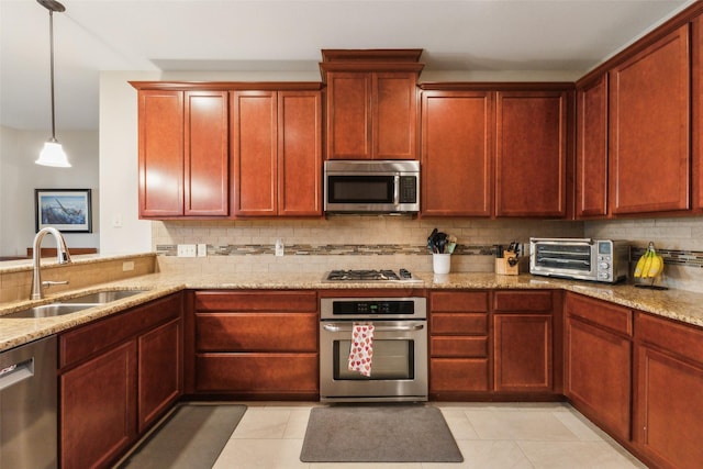 kitchen featuring appliances with stainless steel finishes, pendant lighting, sink, backsplash, and light stone countertops