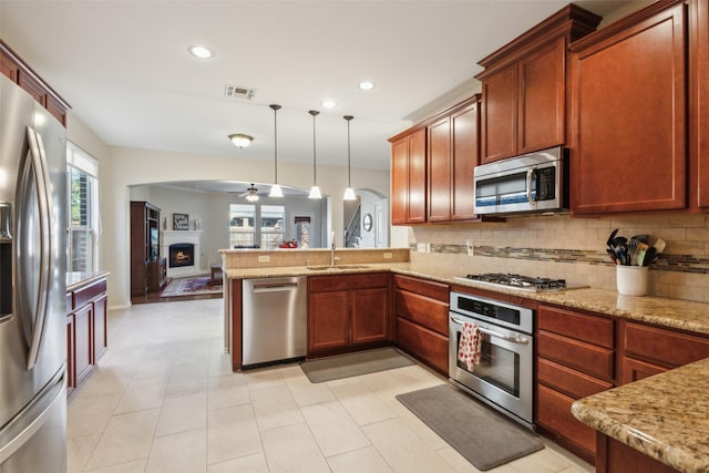 kitchen with sink, hanging light fixtures, stainless steel appliances, tasteful backsplash, and kitchen peninsula