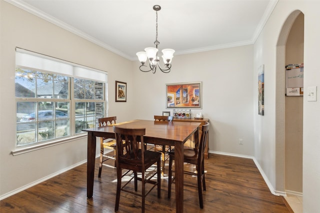 dining space with dark wood-type flooring, ornamental molding, and a chandelier